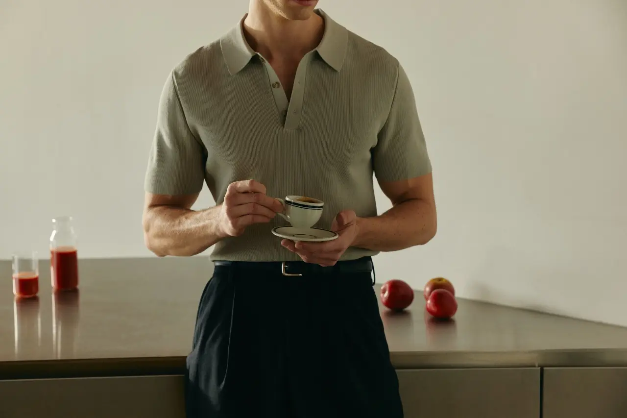 Person holding a small espresso cup in a minimalist kitchen.